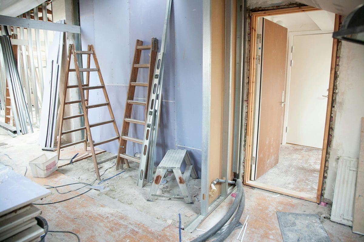 A room being remodeled with ladders and other construction equipment.